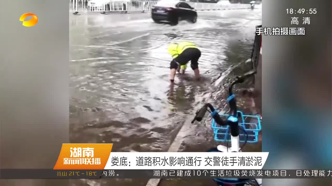 娄底：道路积水影响通行 交警徒手清淤泥